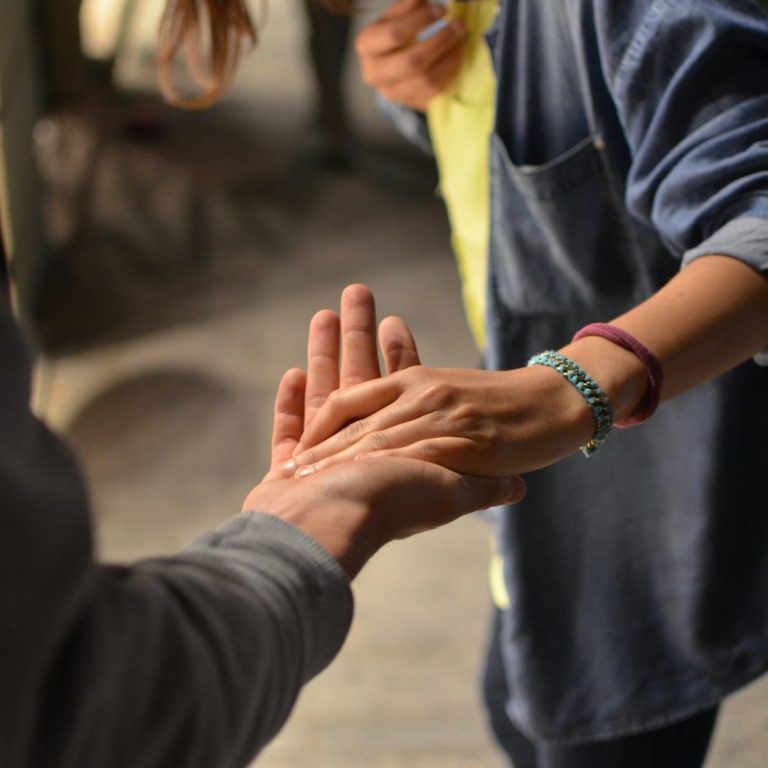 A therapist holding the hand of a client to emphasise compassionate care